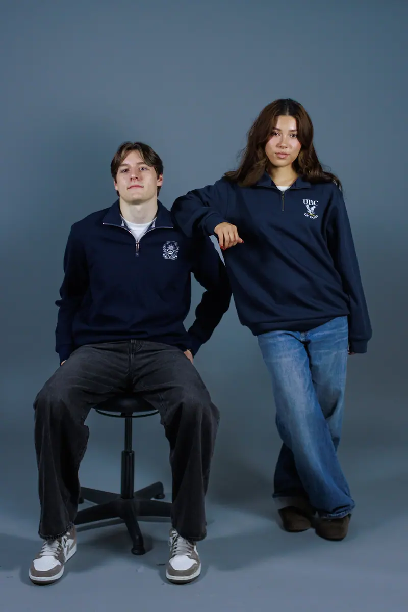 Two students in navy quarter-zips with an embroidered crest