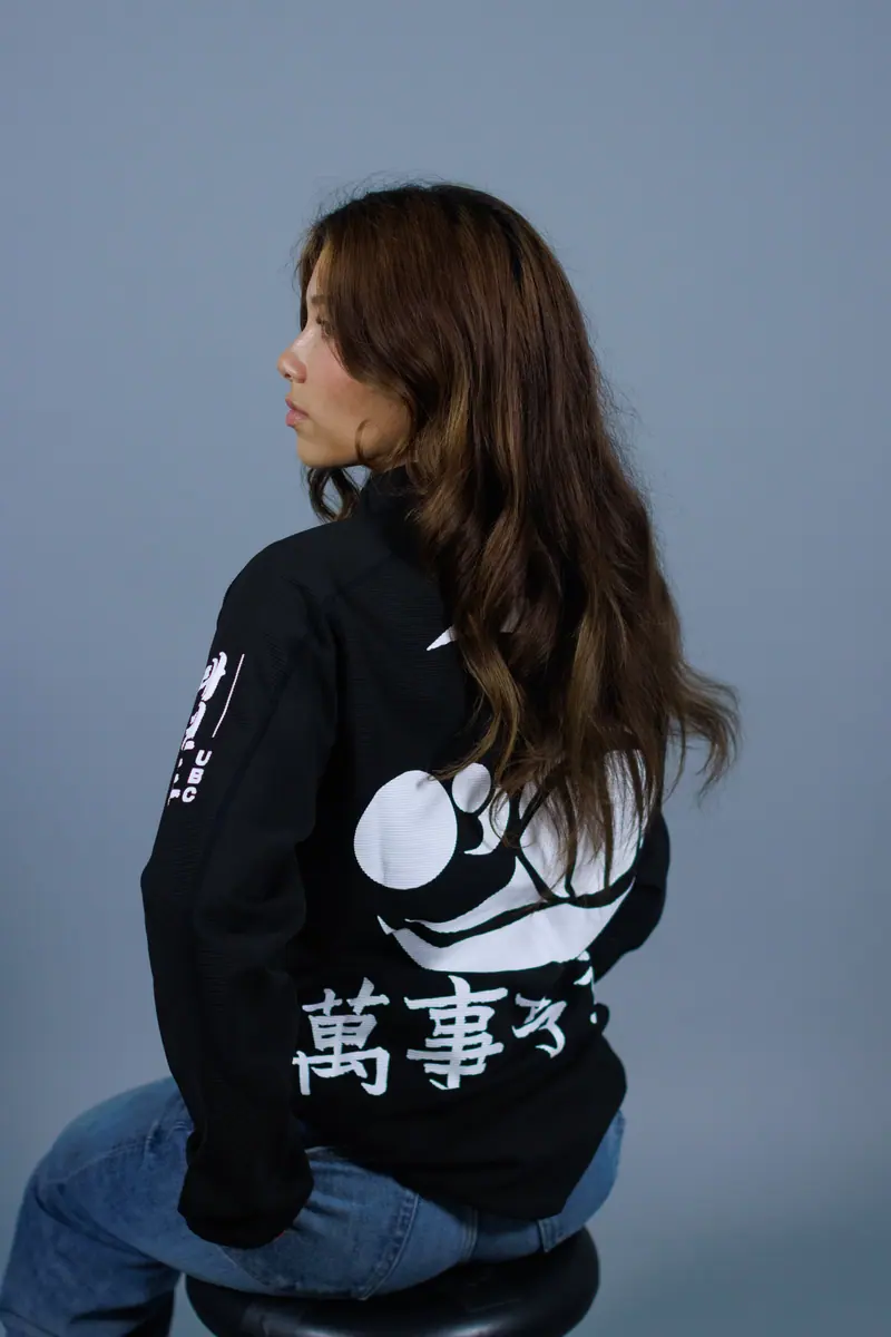 The back of a black team zip-up with a large white print