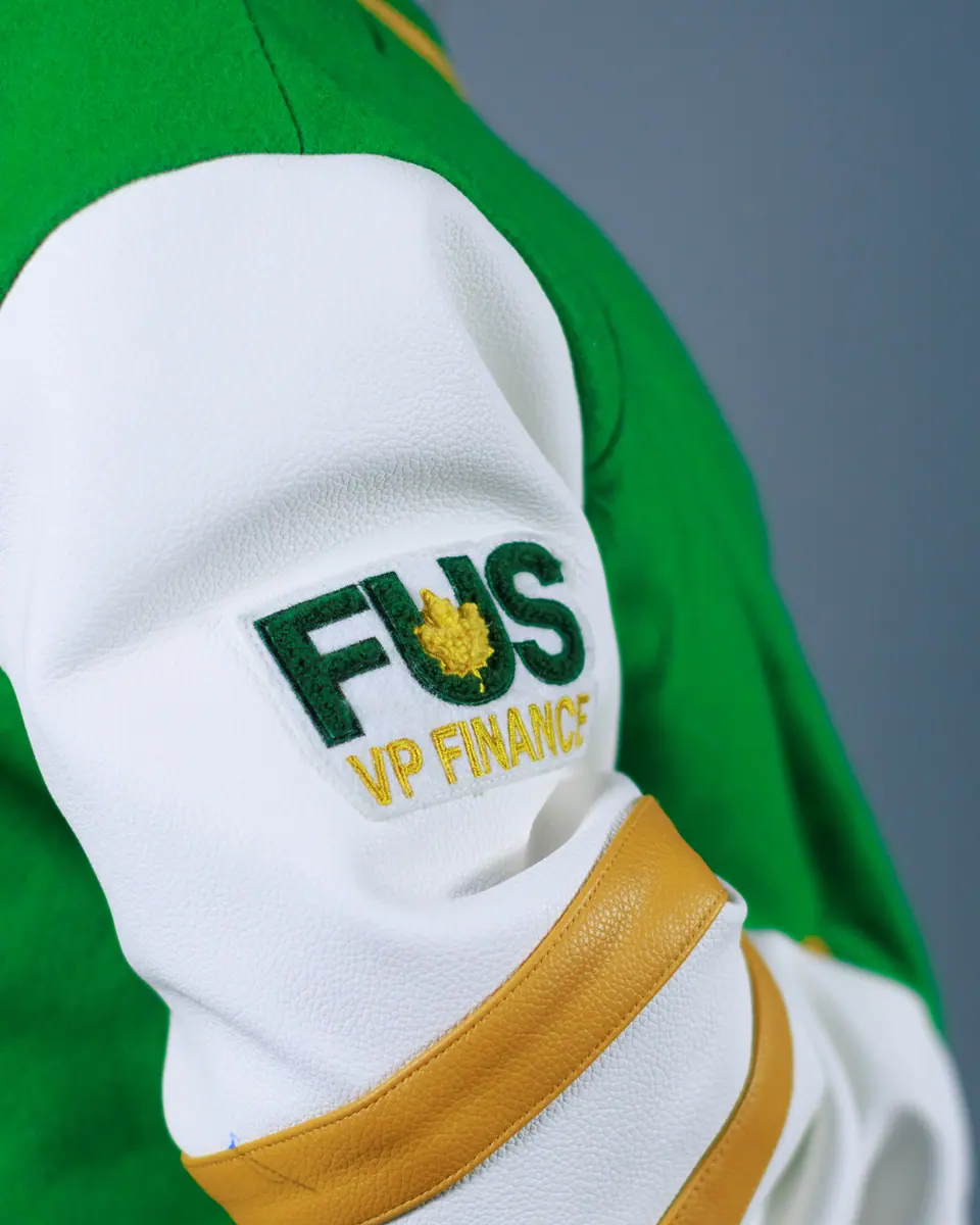 Close-up of an embroidered patch on the sleeve of a green and white varsity jacket